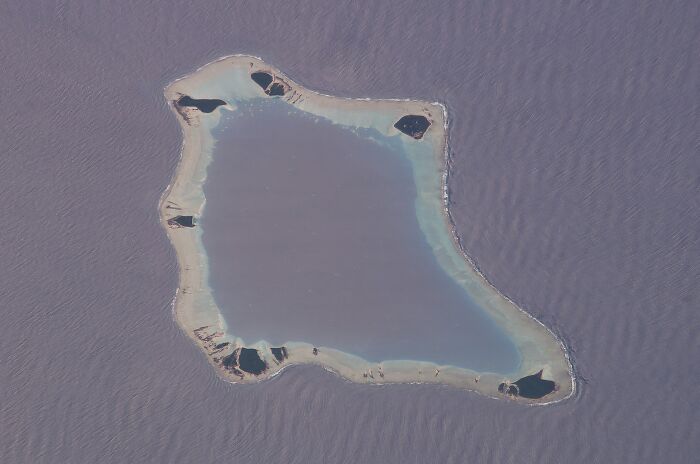 Aerial view of a remote island surrounded by shallow turquoise water, showcasing one of the mind-blowing remote locations.