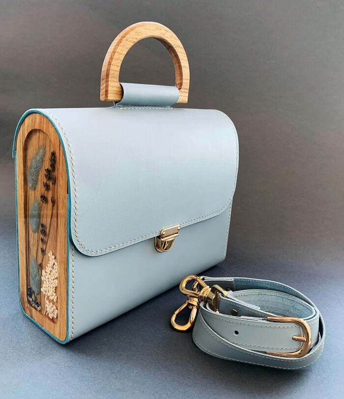 Light blue leather handbag with wooden handle and floral details, showcasing creativity in cool projects by creative people.