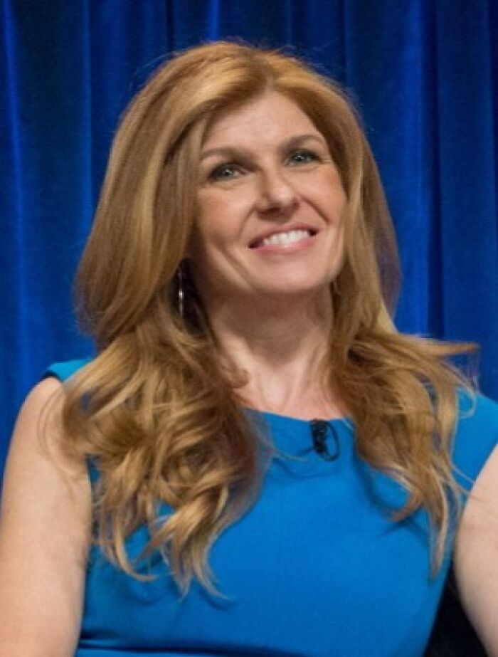 Woman with long red hair wearing a blue dress smiling during a panel discussion about Hollywood stars who found fame after 30.