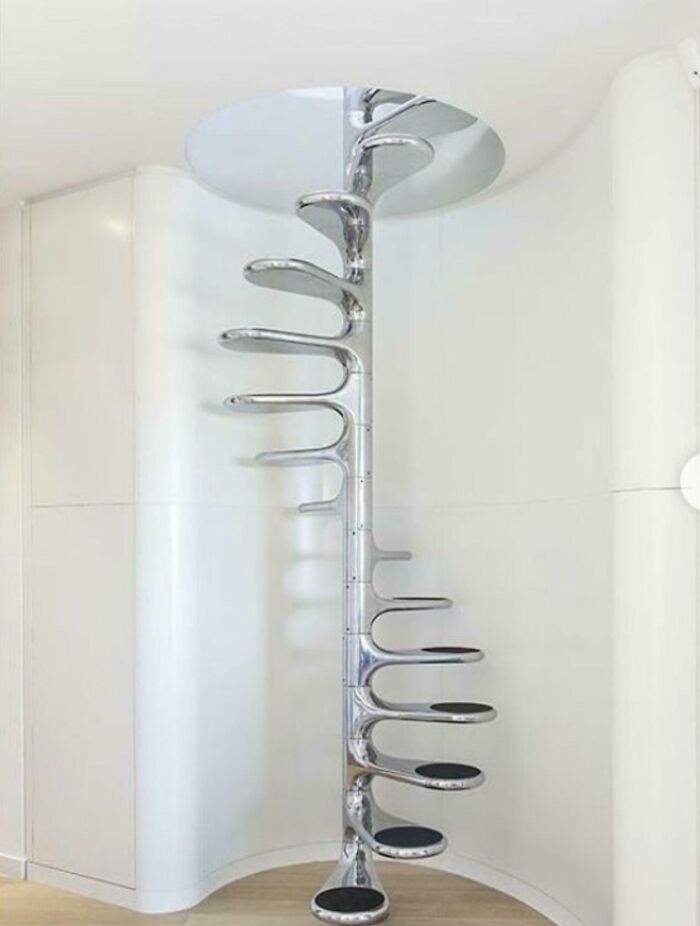 Spiral metal staircase with unusual curved steps inside a modern white room, highlighting Airbnb stairs requiring insurance.