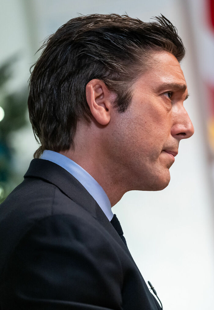 David Muir in a black suit and blue shirt, shown in profile, appearing focused during a formal event or interview.