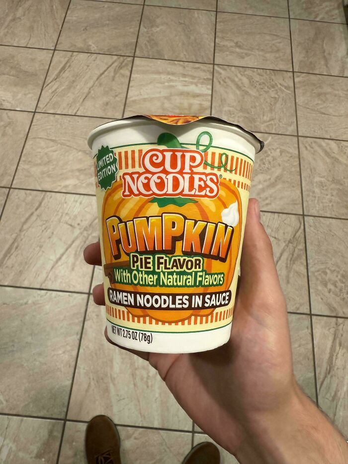 Hand holding limited edition pumpkin pie flavor Cup Noodles ramen, an unusual dish from 102 dishes that are just stupid.