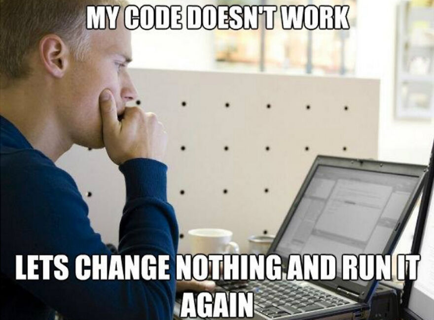 Young man focused on a laptop screen with a humorous programming meme about code not working and debugging struggles.