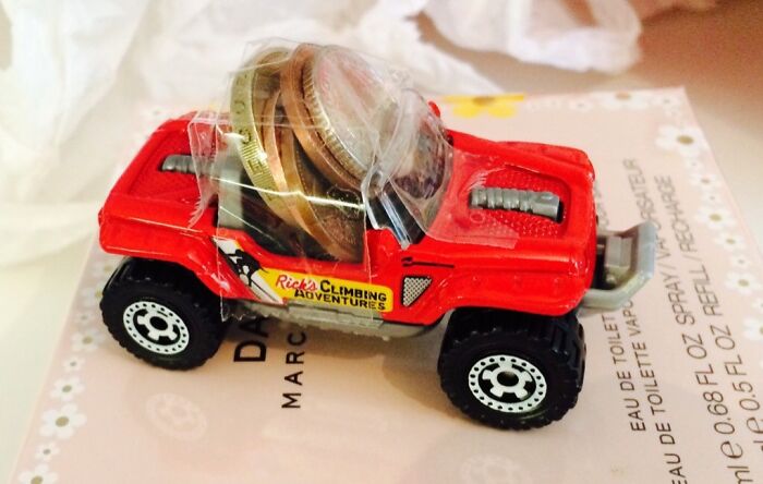 Toy red climbing adventure car filled with coins and taped, illustrating unhinged pics of people doing exactly what they were asked.