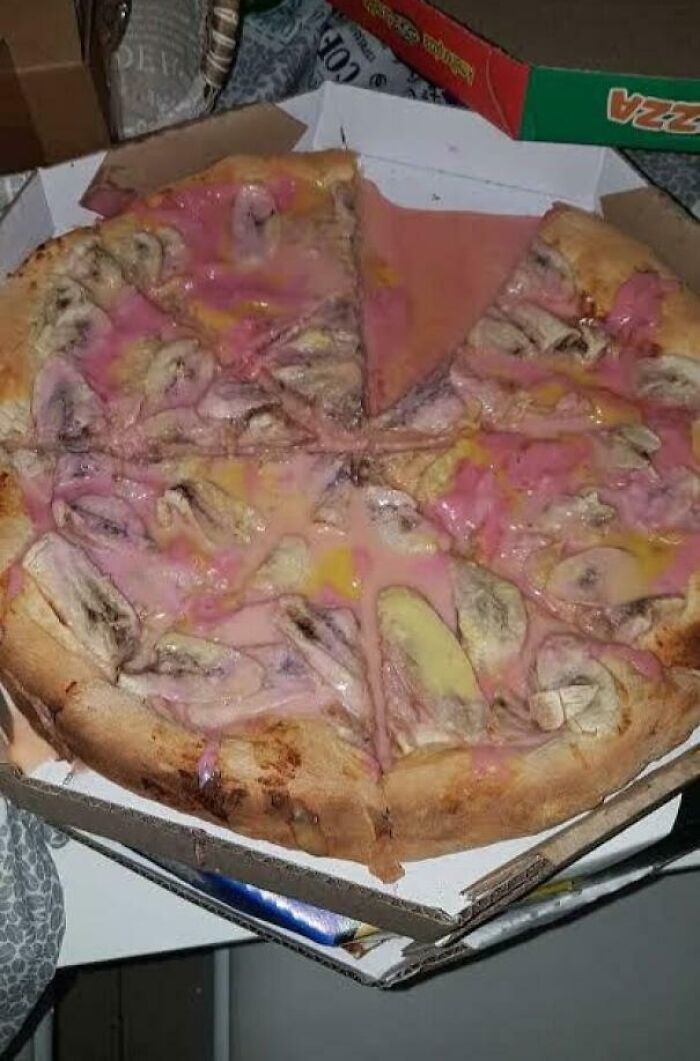 Pizza with unusual pink sauce and banana slices in a delivery box, one of the dishes that are just stupid in appearance.
