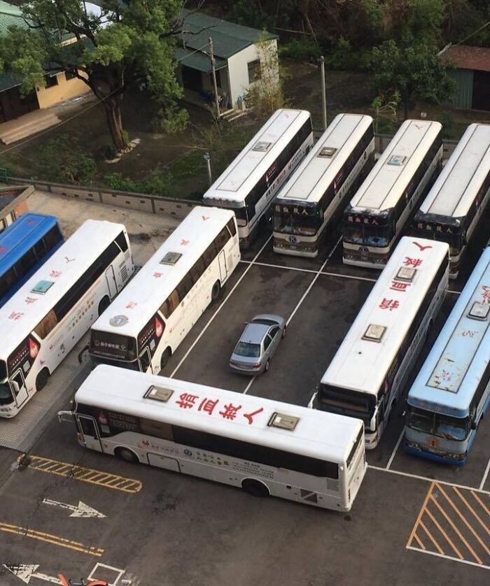 Car blocked by buses parked closely around it, illustrating an example of petty revenge in a parking lot.