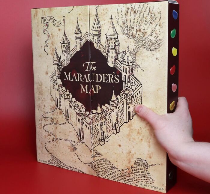 Hand holding a Marauder's Map themed advent calendar with colorful jelly bean compartments for Christmas countdown.