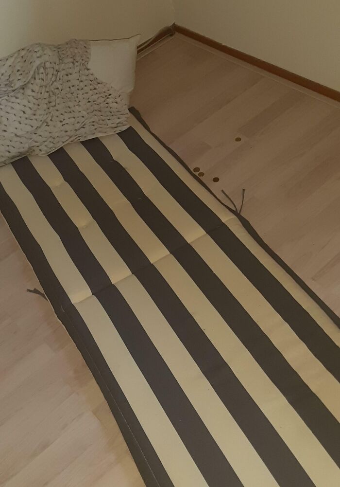 Striped mattress on floor with a blanket and pillow, with coins scattered nearby showing family members' annoying behavior.
