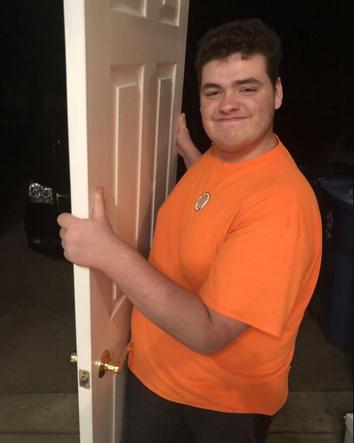 Young man in an orange shirt holding a door with a smirk, illustrating an example of petty revenge moments.