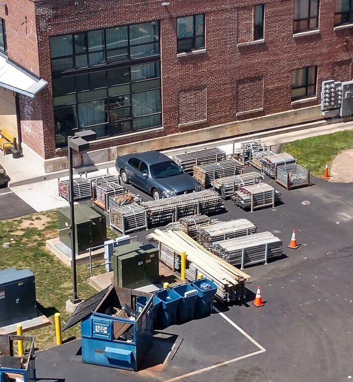 Car blocked by stacked metal fencing and construction materials in a parking lot, illustrating petty revenge example.