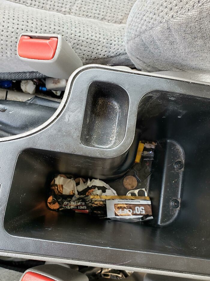 Car center console cluttered with trash and dirt, illustrating frustration with family members in viral online venting posts.