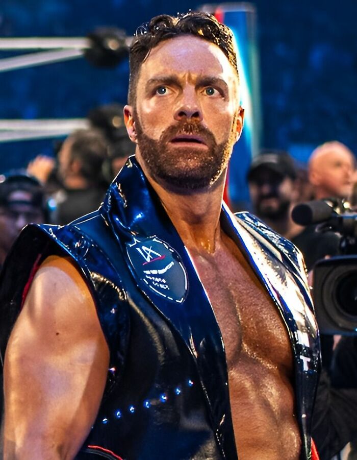 LA Knight in a wrestling ring wearing a shiny vest, showcasing his muscular physique and intense expression.