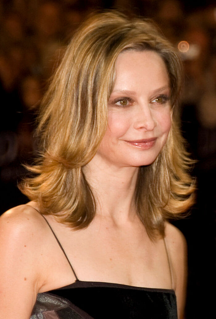 Calista Flockhart smiling at an event with shoulder-length blonde hair and wearing a black dress.