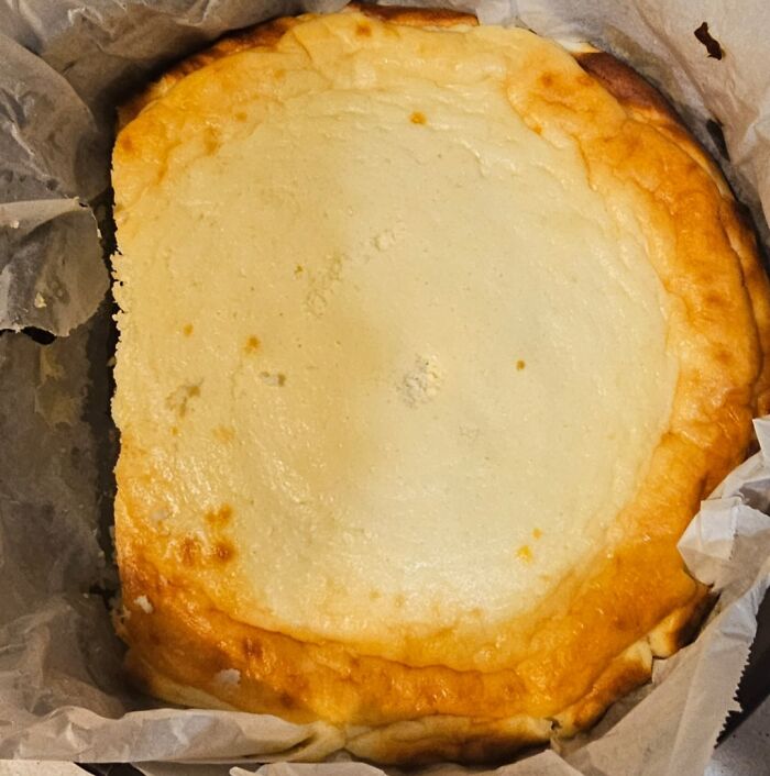 Burnt and oddly shaped cheesecake in parchment paper, a perfect example of family members causing kitchen frustrations.