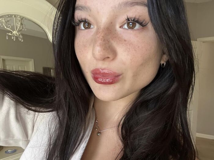 Young woman with long dark hair and glossy lips, showcasing viral products popular on TikTok algorithm trends.