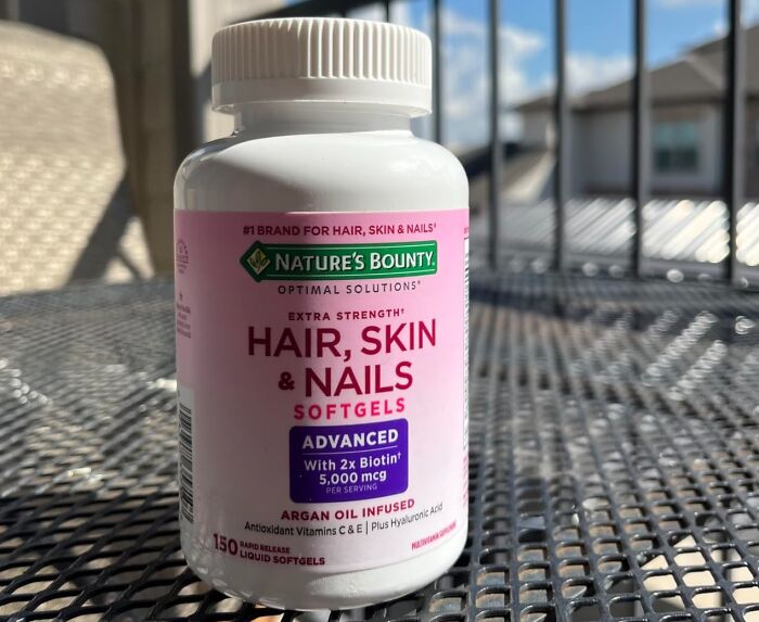 Nature’s Bounty hair skin and nails softgels bottle on metal table, a viral product trending on TikTok algorithm.