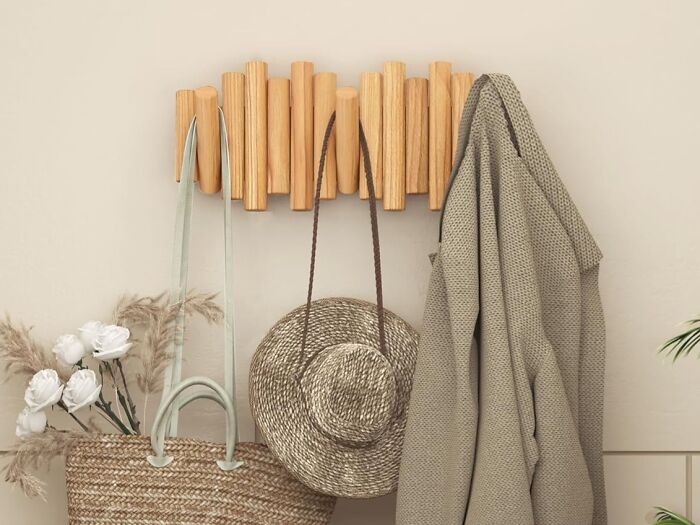 Wooden wall hooks holding a woven bag, a straw hat, and a cozy beige sweater, showcasing viral products trending on TikTok.