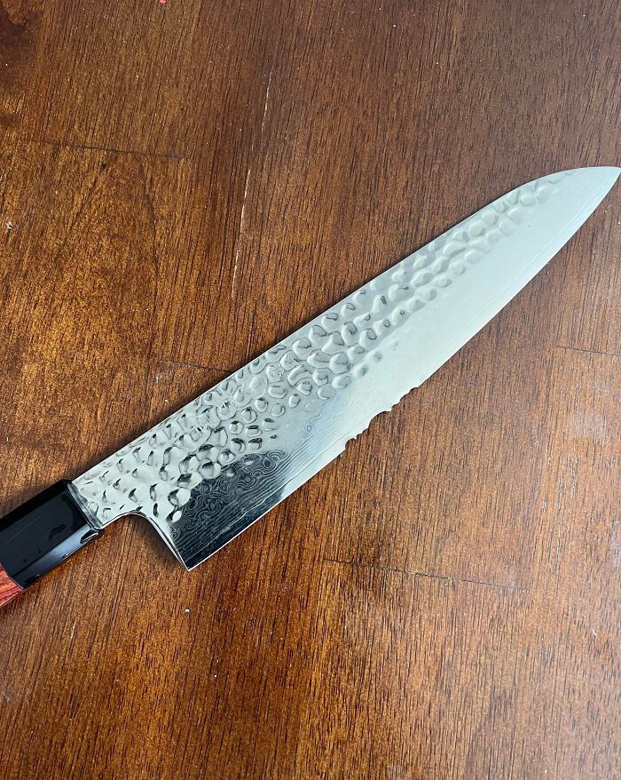 Close-up of a hammered steel kitchen knife on a wooden surface, illustrating frustration with family members online.