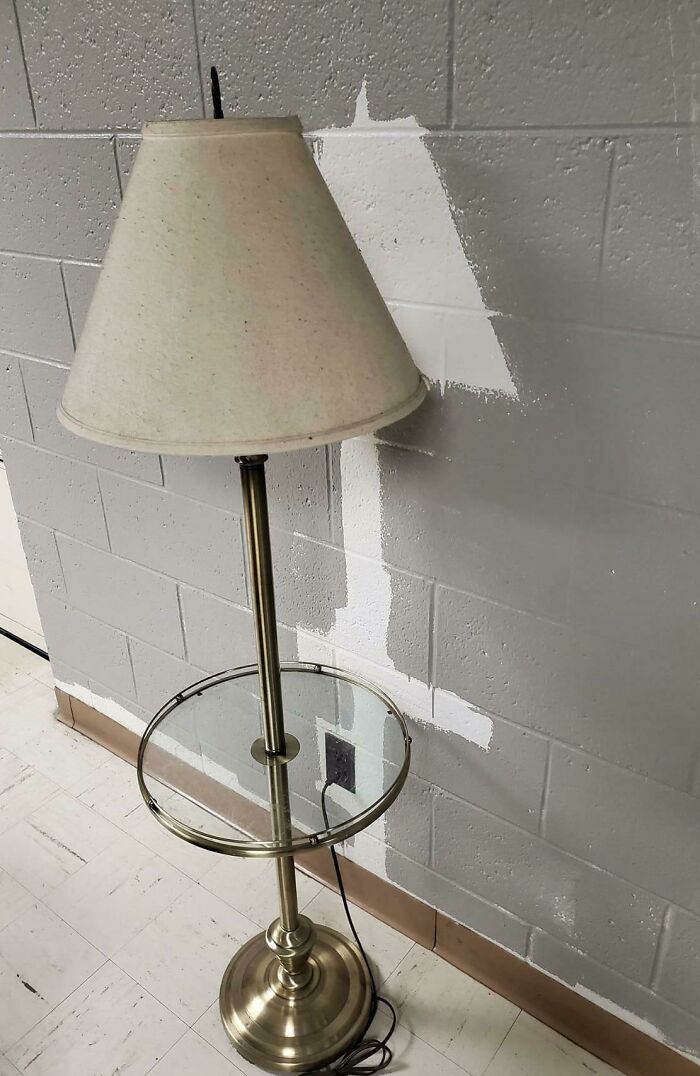 Floor lamp placed in front of unpainted patch on wall showing a funny example of people not even trying.