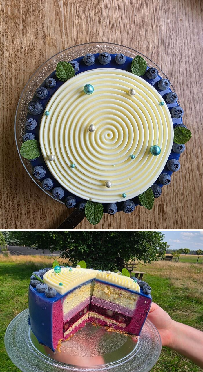 Elegant baked goods featuring a spiral white frosting cake with blueberries and mint leaves on a glass plate.
