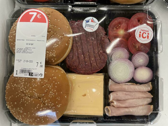 Burger kit with sesame buns, raw patties, cheese slices, onions, tomatoes, and ham in a clear plastic container solving meal prep problems