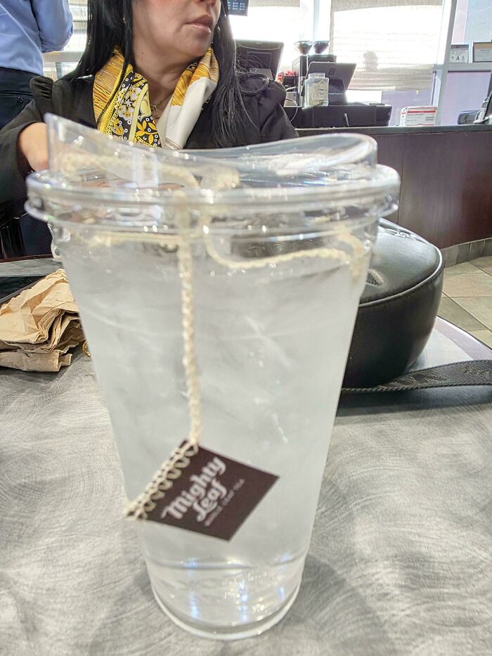 Clear plastic cup with lid holding iced water and a hanging tea bag, showcasing smart ideas and inventions solving problems.