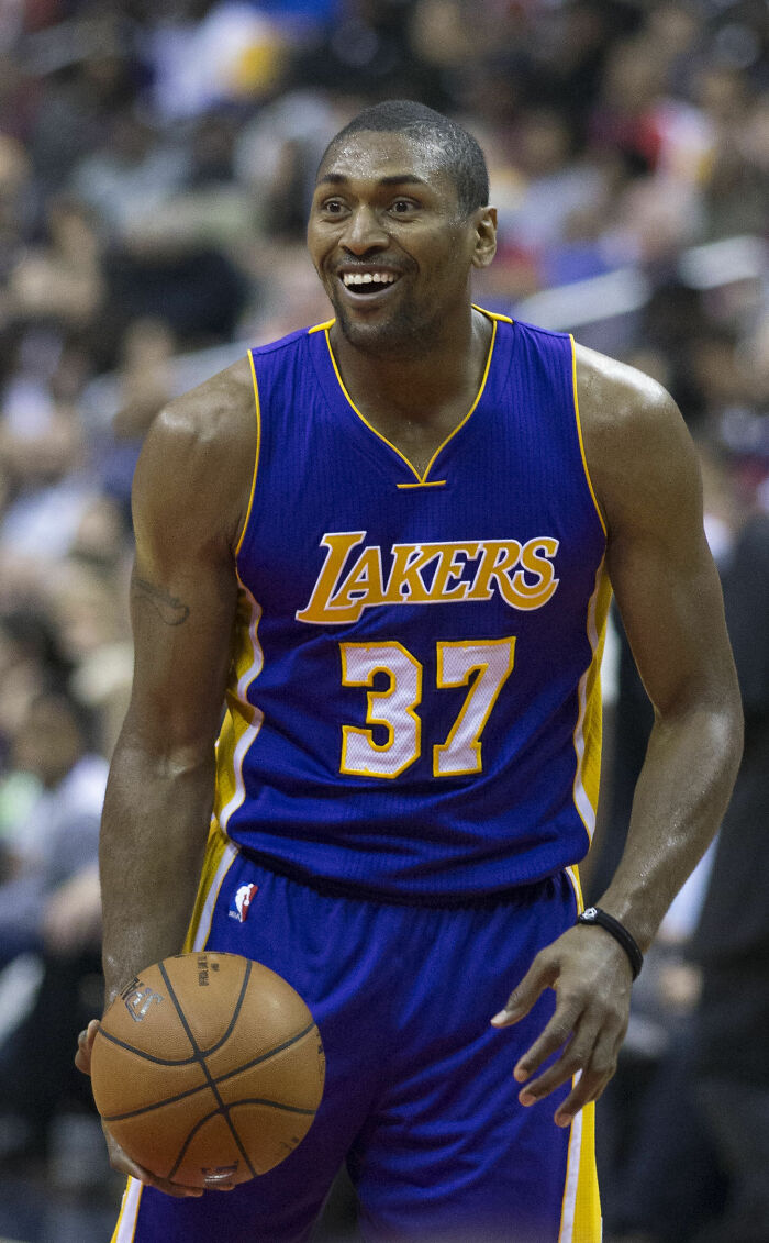 Metta Sandiford-Artest in Lakers jersey number 37, holding basketball and smiling during a game on the court.