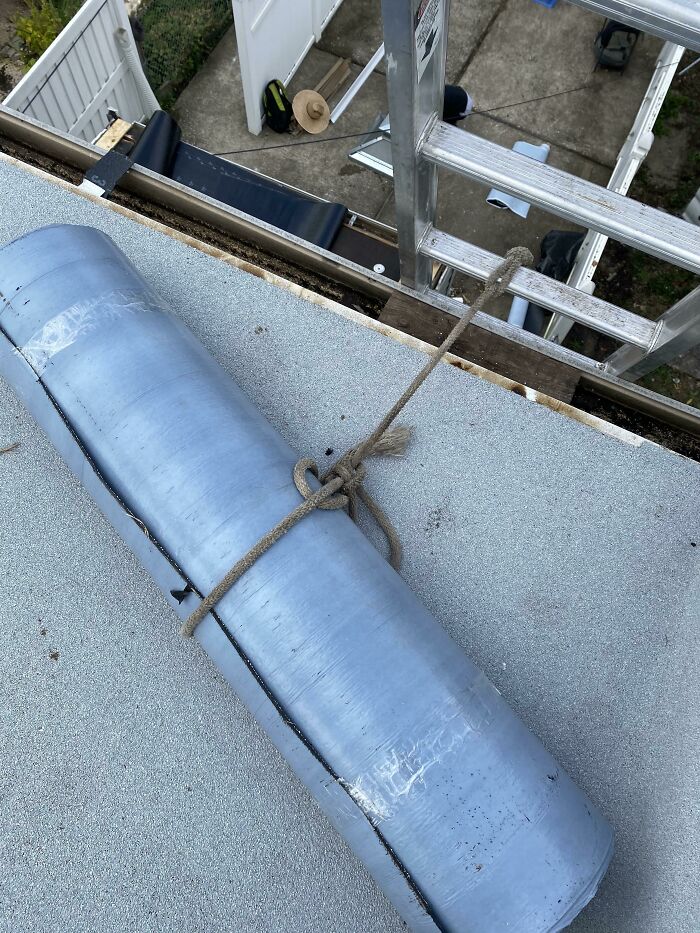 Rolled roofing loosely tied with rope on rooftop next to ladder showing funny examples of people not even trying.