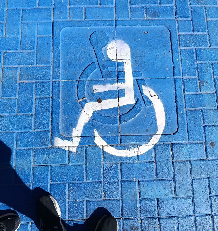 Creative example of people not even trying shown by a poorly painted wheelchair symbol on blue pavement.