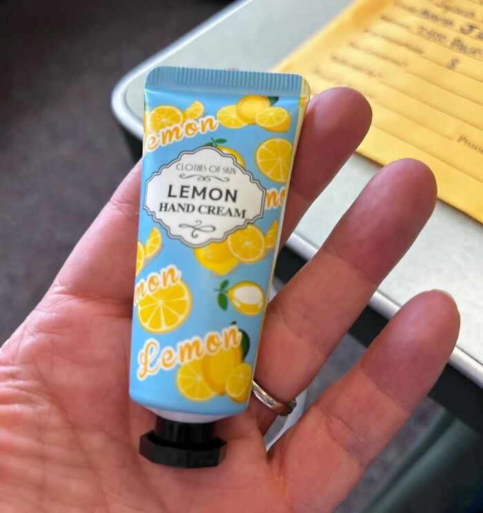 Hand holding lemon hand cream tube, a cozy burr basket essential for self-care and hibernating during winter months.