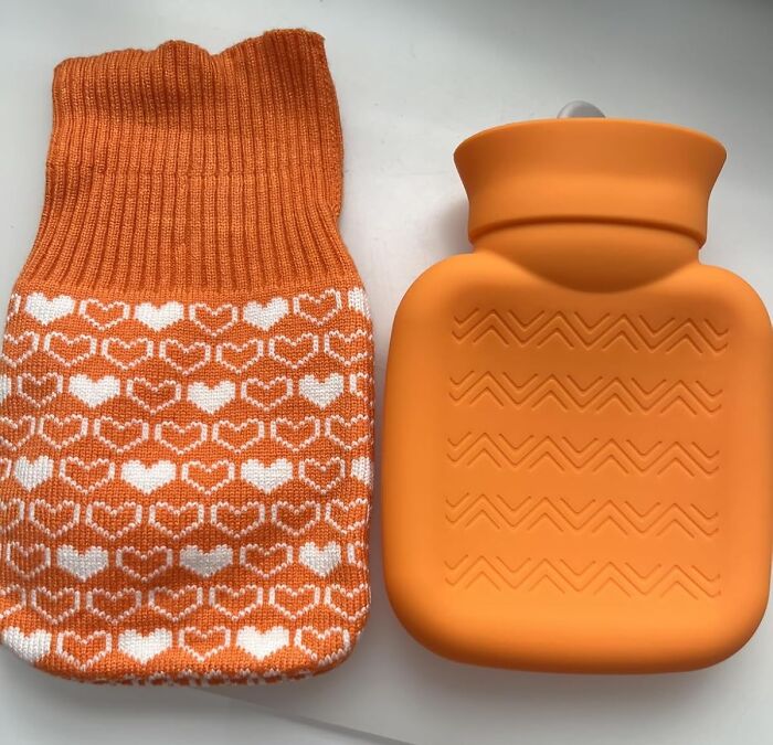 Orange hot water bottle and cozy heart-patterned cover, winter burr basket goodies for staying warm and comfortable.