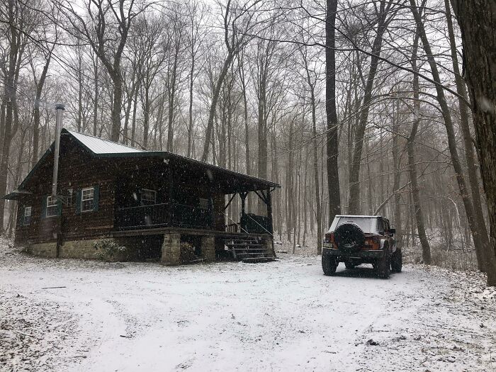 Cozy off-grid cabin in a snowy forest setting with a parked SUV nearby, perfect for disconnecting from everything.