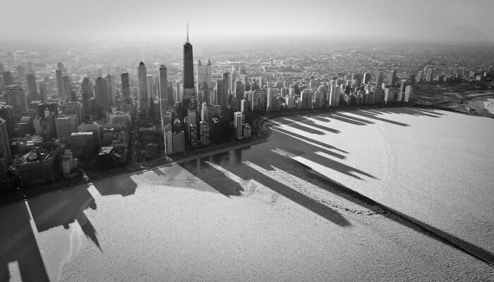 Aerial black and white view of a city skyline casting long shadows, showing our world from a different perspective.