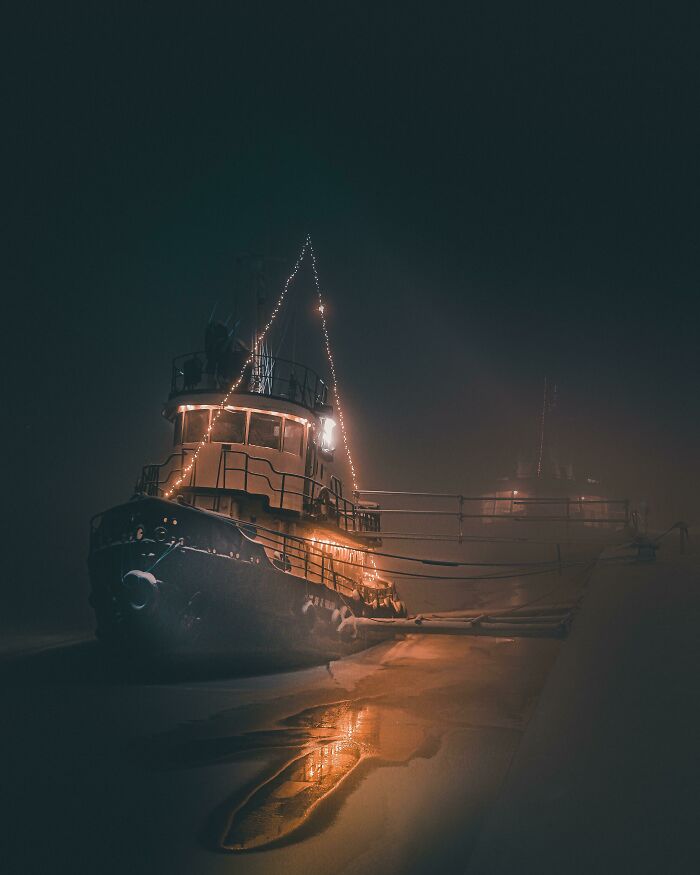 Boat decorated with glowing lights moored at night in fog, showing our world from a different perspective.
