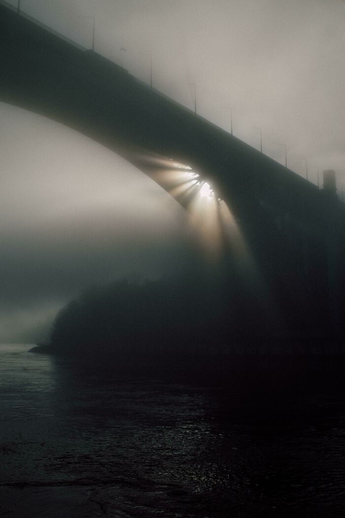 Sunlight beams through a foggy bridge arch, creating a stunning view that shows our world from a different perspective.