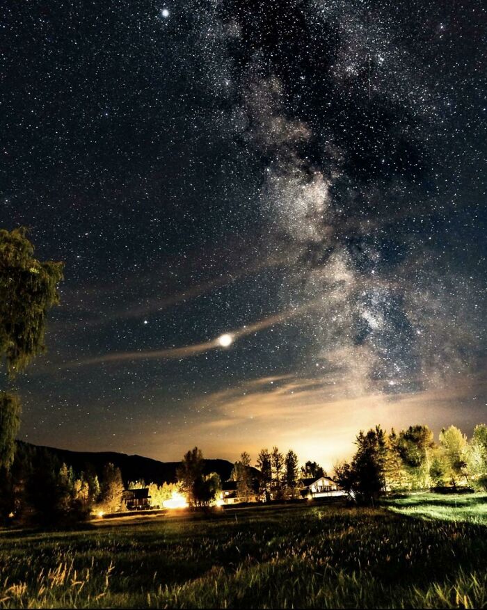 Night sky full of stars and the Milky Way over a brightly lit rural landscape showing a different perspective of our world.