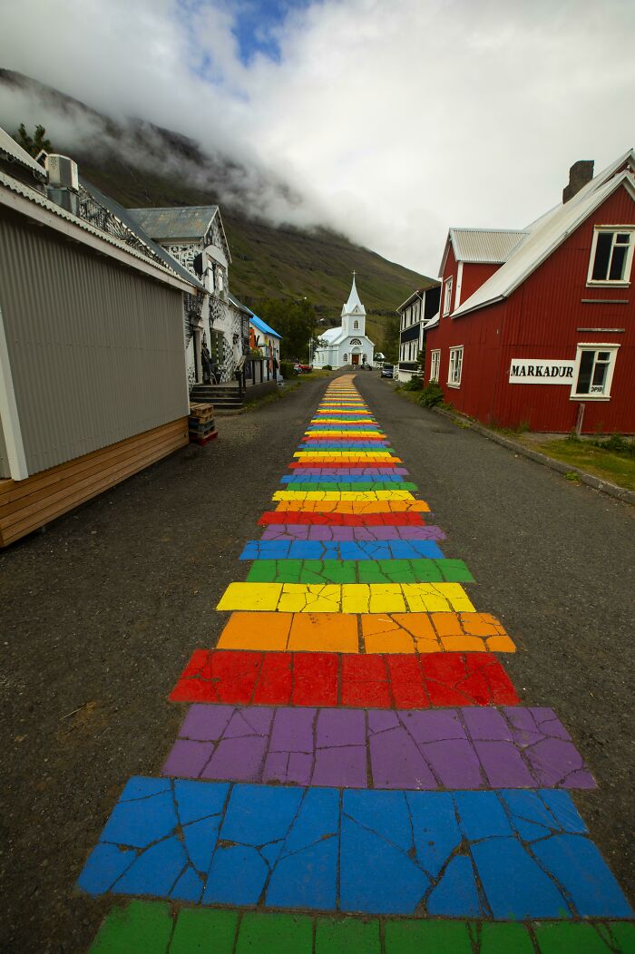 A colorful rainbow pathway leading to a white church in a small town, showing our world from a different perspective.