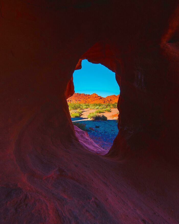 View of desert landscape through a natural rock formation showcasing a unique world perspective with vibrant colors.