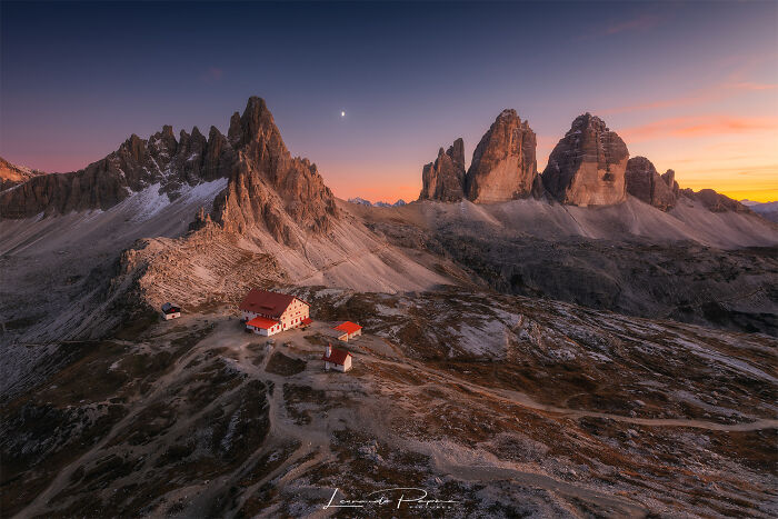 Aerial view of mountain peaks and small buildings at sunset, showcasing amazing pics of our world from a different perspective.