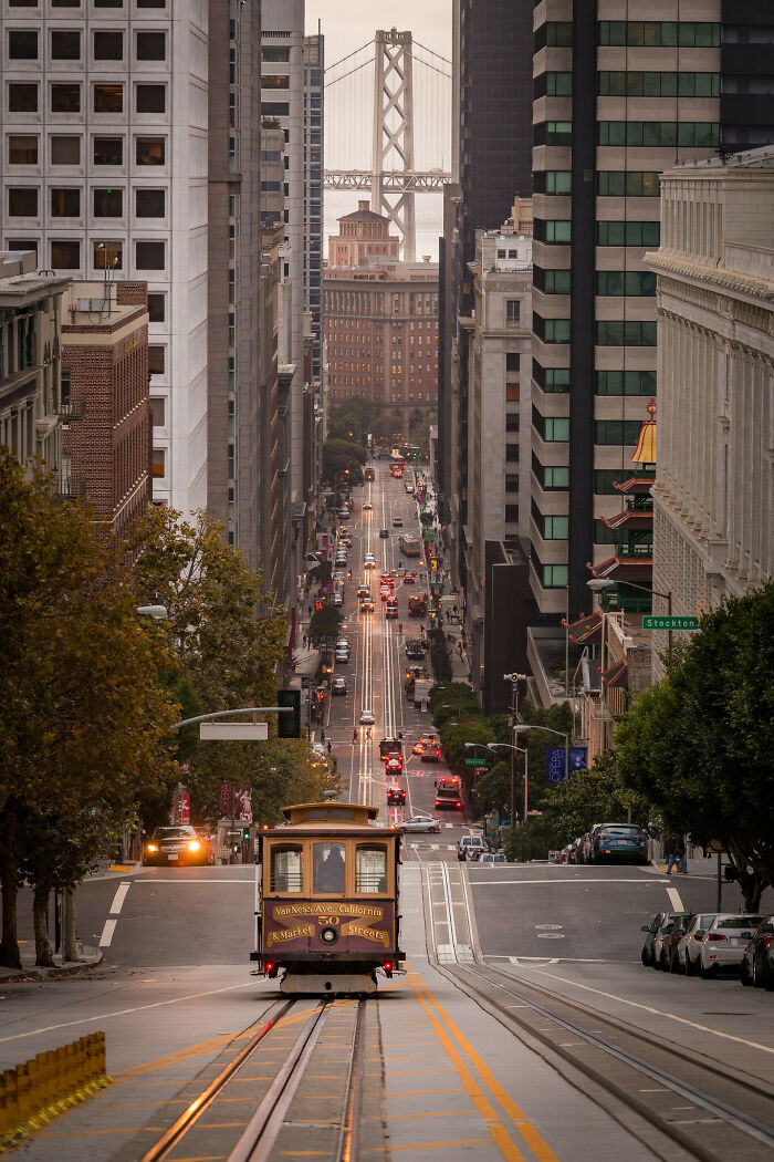 Cable car moving down a steep city street lined with tall buildings showcasing a unique perspective of urban life.
