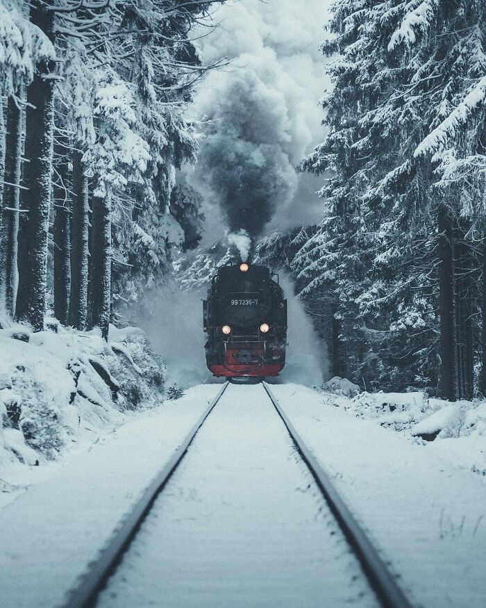 Steam train moving through snowy forest, showcasing an amazing perspective of our world in winter.