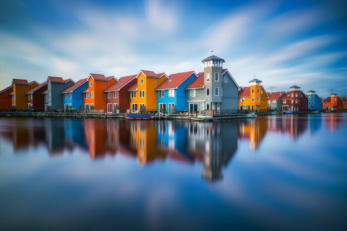 Colorful houses reflecting on calm water, showcasing amazing pics of our world from a completely different perspective.