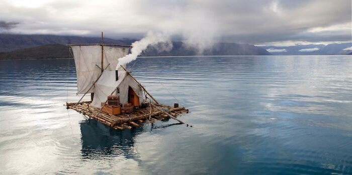 A rustic raft with sails and smoke, floating on calm water, showing our world from a different perspective.