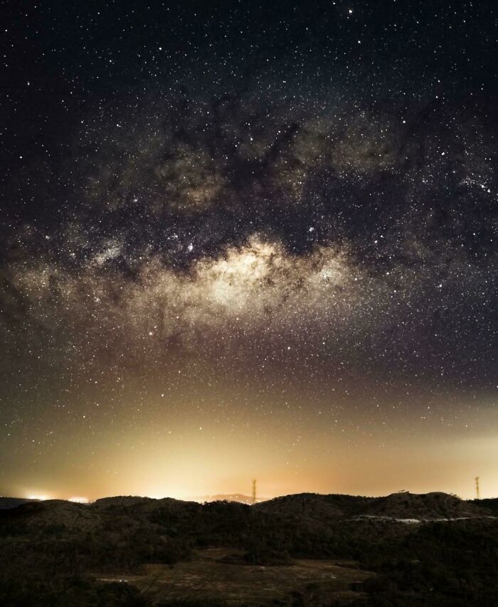 Starry night sky over dark hills, showcasing an amazing view of our world from a completely different perspective.