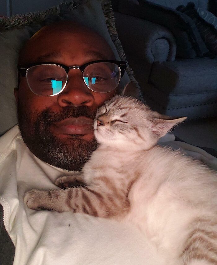 Man and cat cuddling on couch showing times people got a pet and had to say goodbye to personal space.