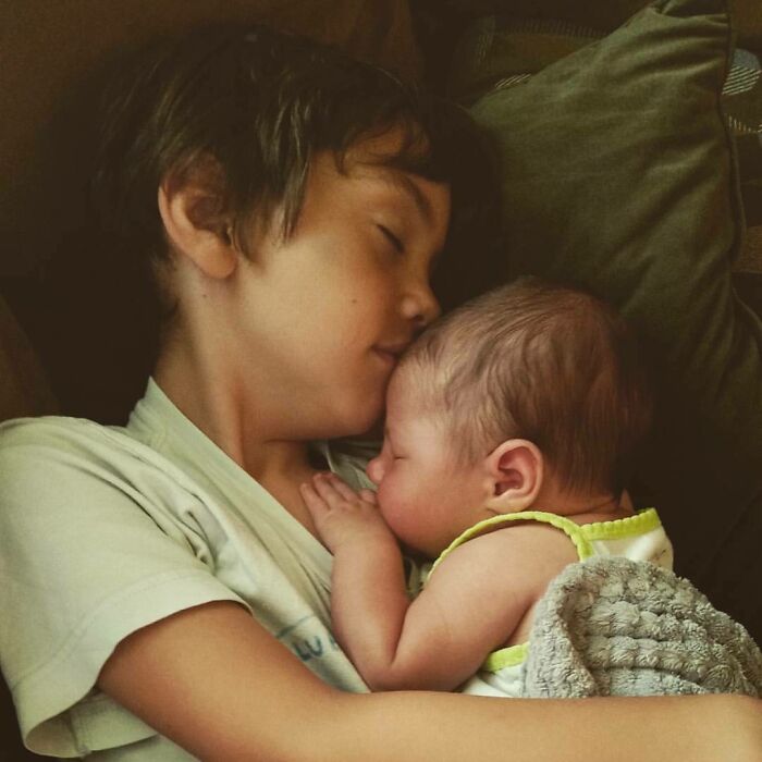Young boy holding and cuddling a sleeping baby, capturing a heartwarming moment of dreams turned into reality.
