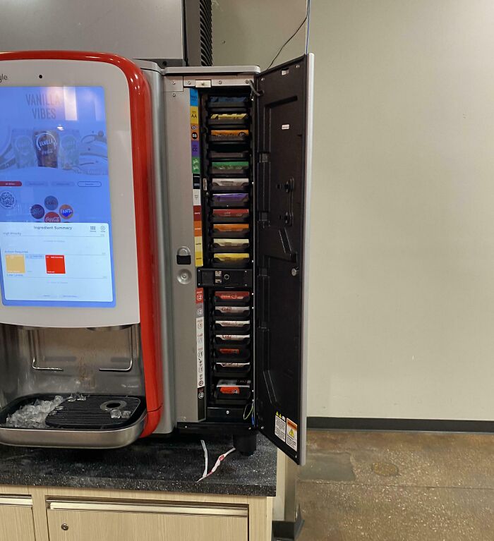 Inside view of a soda machine showing internal syrup cartridges and electronic components, revealing how the object looks inside.