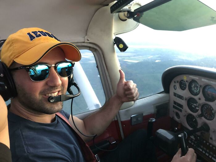 Man wearing sunglasses and headset giving thumbs up in cockpit, showing people turning dreams into reality inspiration.
