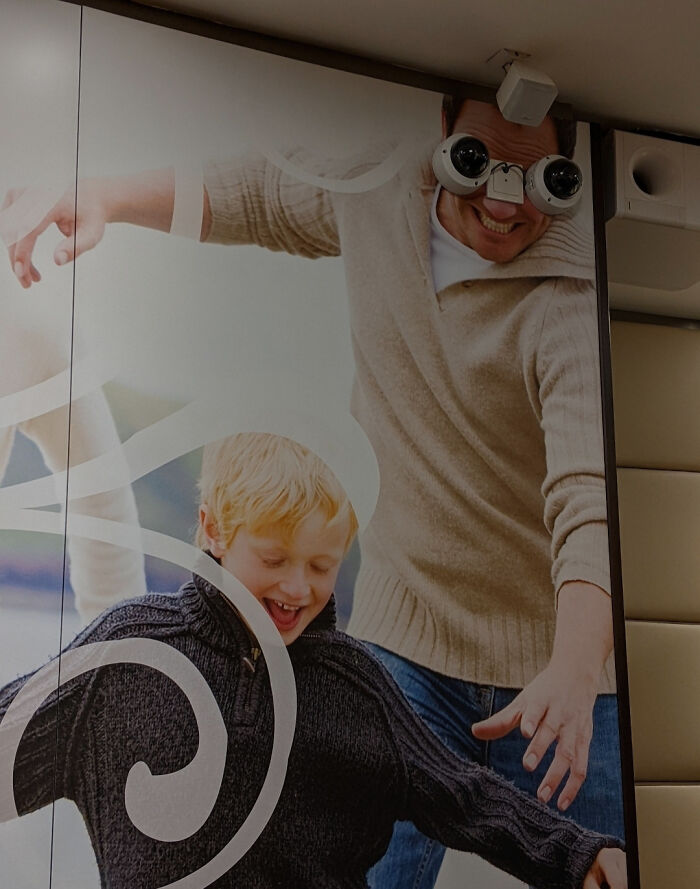 Man wearing makeshift funny binoculars playing with a child, illustrating humorous examples of people not trying at work.