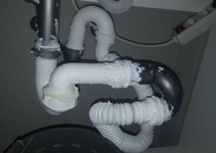 Poorly fixed plumbing pipes with messy white sealant, showing a funny example of people not even trying to do the job properly.